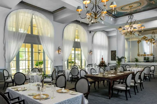 Indoor dining room with large white curtains and wine glasses on the tables