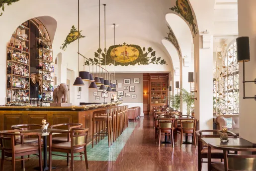 Indoor bar with wooden chairs and tables and a statue of an elephant to the left