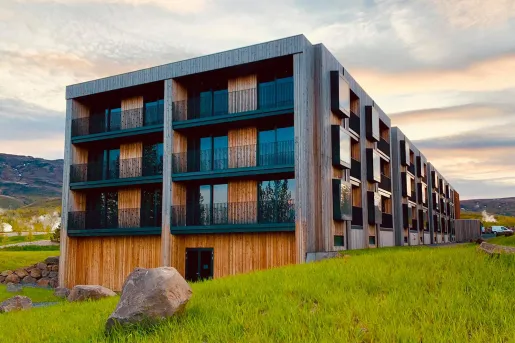 Exterior view of wooden hotel building with balconies and large mountains in the distance
