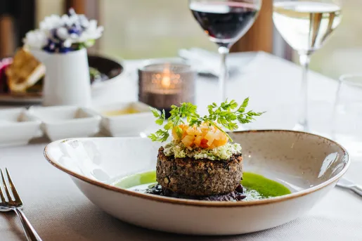 Plate with a small piece of steak in the center, on a table with a  tablecloth