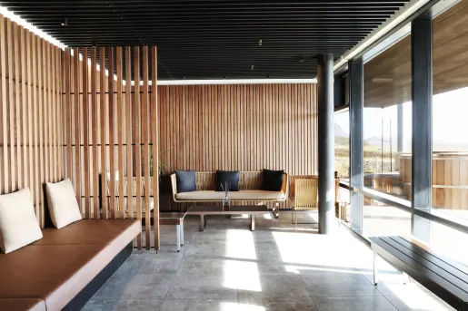 Indoor seating area with leather, cushioned chairs looking out to an outdoor sauna