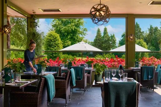 Waitress prepping dining tables with large open windows behind