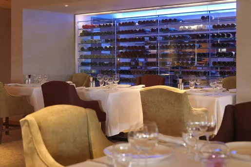 Dining area with wine glasses and a glass case full of wine bottles in the background