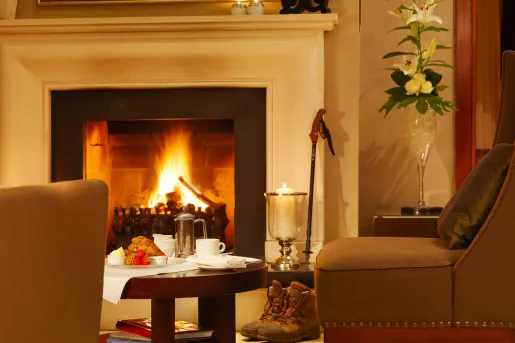 Leather couch in front of a white fireplace, with pastries and fruit on a circular coffee table