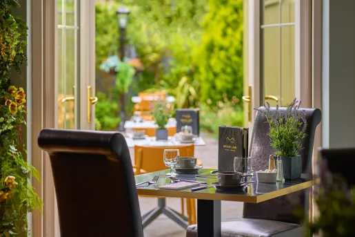 Dining area with tall, leather chairs with an open door in the background