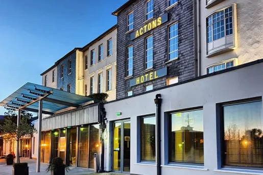 Exterior view of stone hotel building with large windows along the walls