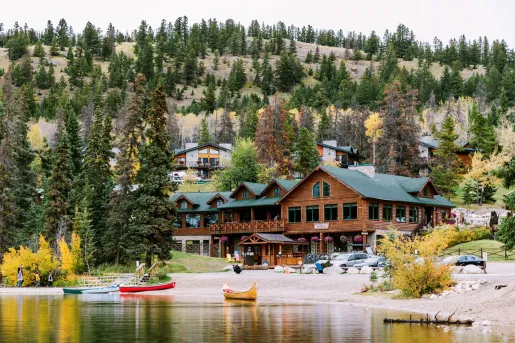 Exterior view of wooden cabin-styled building next to a lake with small boats in front