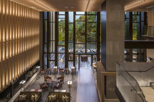 Indoor hotel lobby with large wooden panels on the walls and large windows looking out to the forest