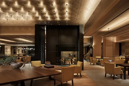 Indoor lounge area with tan cushioned seats surrounded a black fireplace