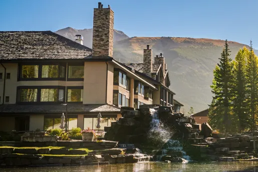 Outdoor view of a hotel with open windows and a stone fountain