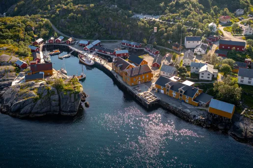 Sky view of orange and red buildings next to a cliff and a body of water