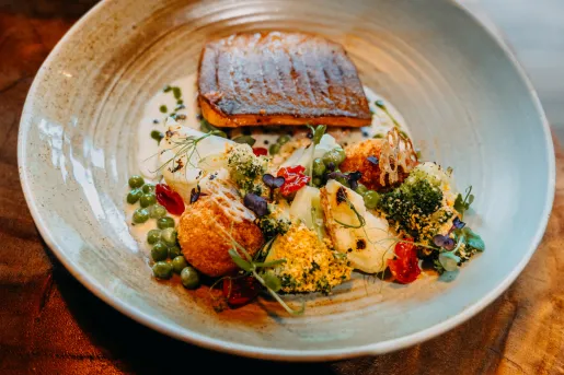 Plate of grilled fish and decorated, prepared vegetables