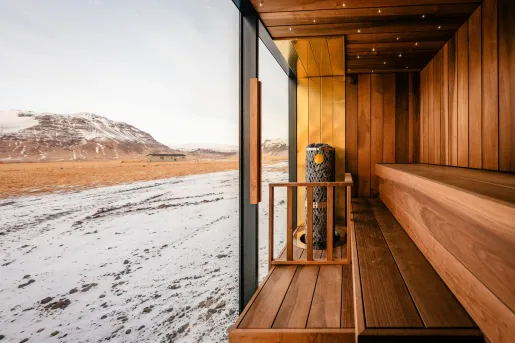 Wooden sauna with large, glass walls viewing out to a snowy mountain