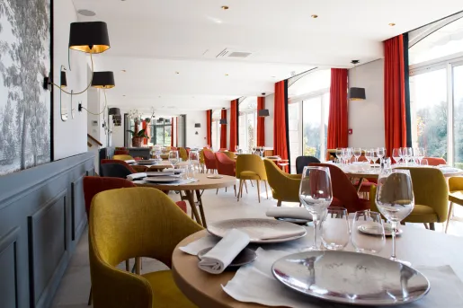 Long dining area with wine glasses and plates on each table