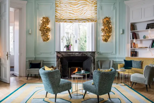 Two blue, cushioned chairs in front of a fireplace in a lobby