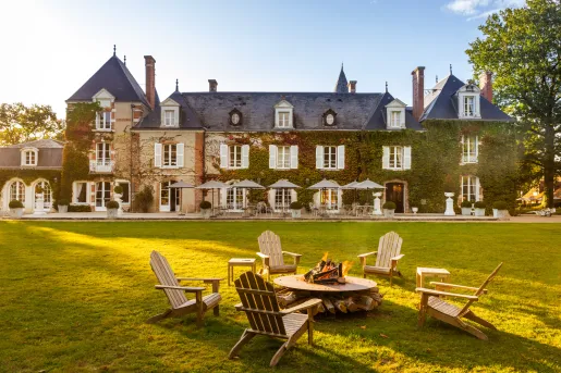 Exterior view of tan and blue hotel building, covered in green plants with a grass field in front