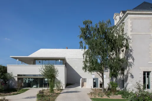 Modern, white building with large, glass doors and trees in front