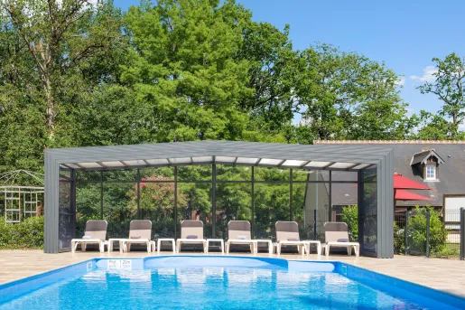 Outdoor pool with brown chairs under a glass canopy covering