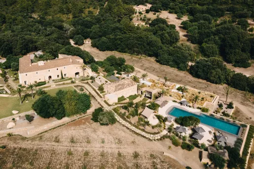 Top view of large white buildings and an outdoor pool surrounded by trees