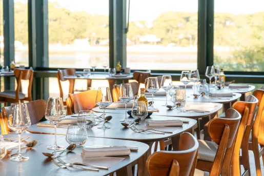 Long dining table with wooden chairs and wine glasses on either side