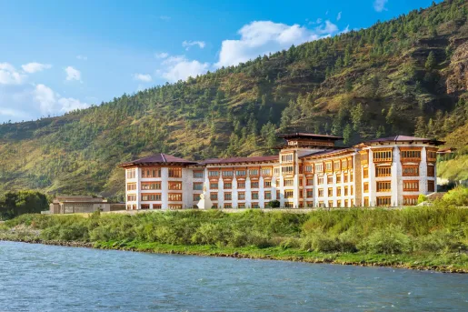Exterior view of white and gold hotel building next to a lake
