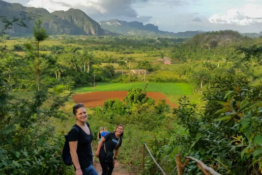 Group of women hiking up a dirt trail, with large valley in the distance