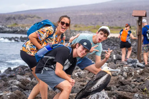 Three teenagers pose with a bird