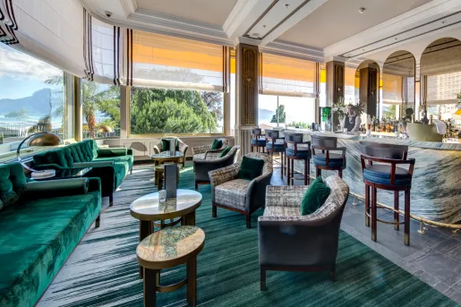 Bar and lounge with large open windows and a bartender in the background