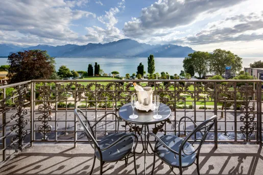 Balcony with two metal chairs and a table with a bottle of alcohol on it
