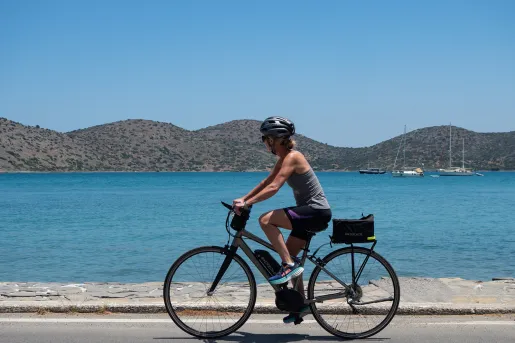 Woman on an e-bike along a road next to the ocean