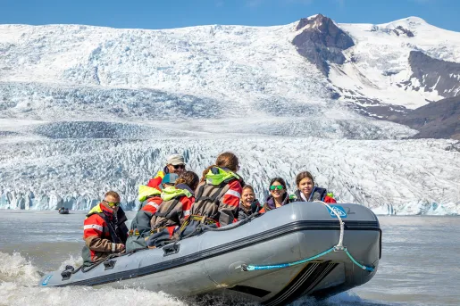Group of people on a gray raft with snow mountains in the background