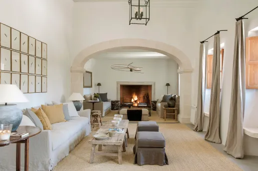 Indoor lobby with cushioned couches, long curtains and a fireplace in the back
