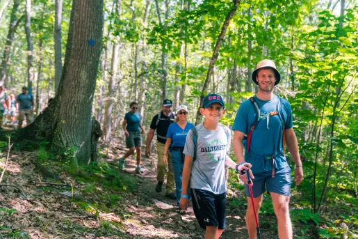 Group of families hiking on a dirt trail in a forest