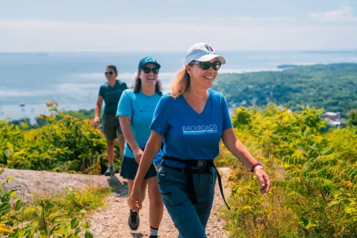 Three women smiling as they are hiking on a dirt trail