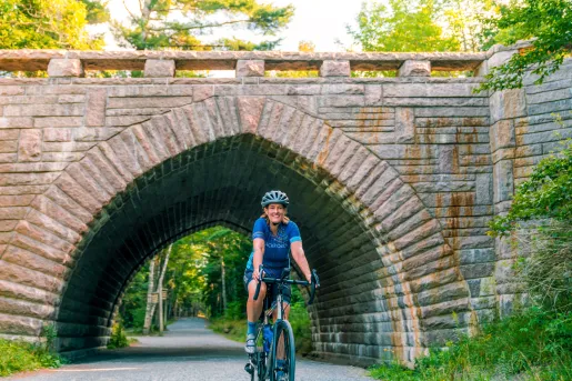 Woman smiling while riding a bike through a brick tunnel