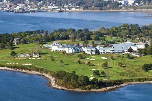Sky view of large white buildings in the middle of a grass field on a peninsula