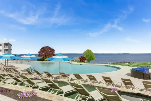 Outdoor pool with blue umbrellas, looking out to the ocean in the distance