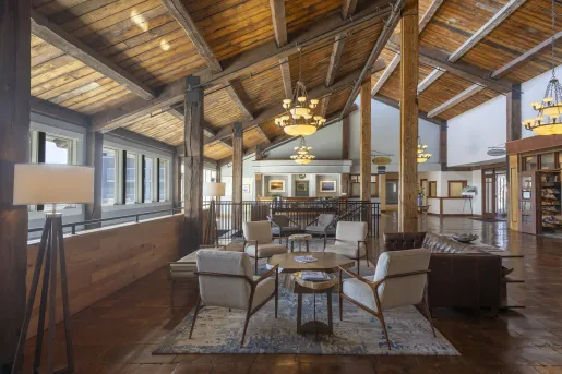 Indoor cabin lobby, with wooden pillars and tan chairs around a coffee table