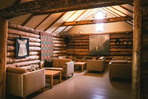 Wooden cabin room with cushioned chairs and paintings on the walls