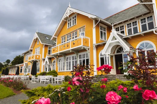 large yellow house flanked by rose bushes