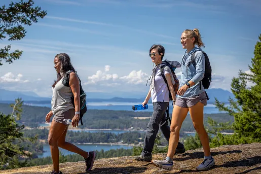 Group of three women hiking down a dirt path on a hill