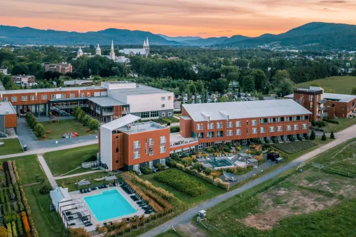 Exterior view of orange and gray building complex, with tall trees and giant churches in the background