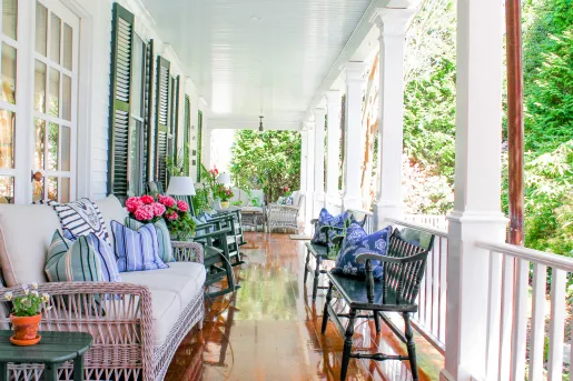 Outdoor porch of a white building with cushioned reclining chairs