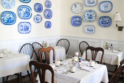 Dining hall with wooden chairs and blue and white plates hanging on the wall