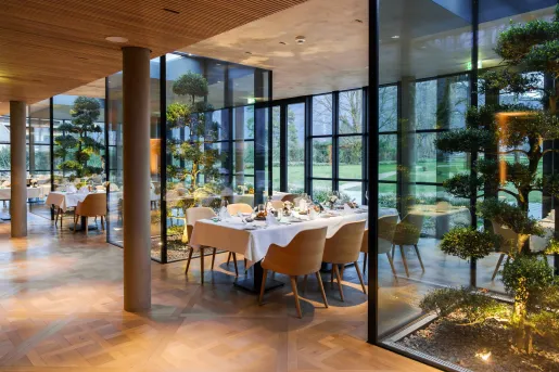 Indoor dining area with 5 long dining tables and trees in glass containments