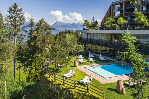 Outdoor view of hotel's outdoor pool, surrounded by umbrellas and pool chairs