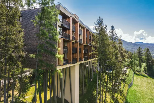 Elevated hotel building with multiple balconies overlooking a grass valley