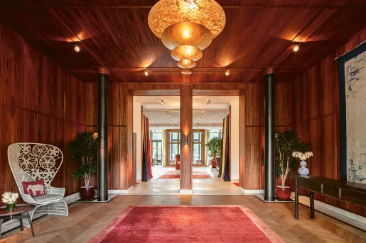 Wooden building entrance with a red carpet and black pillars