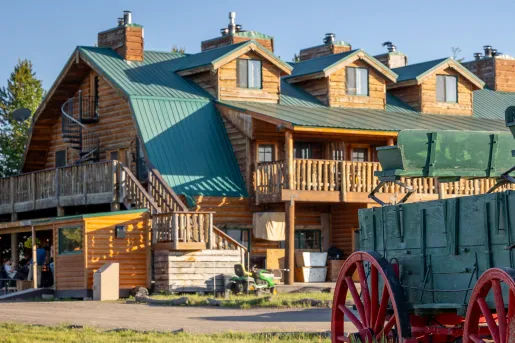 Wood cabin with a green roof, and a green wagon in front