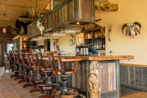 Wooden bar with wooden bar stools, with dried bull skulls hanging on the wall